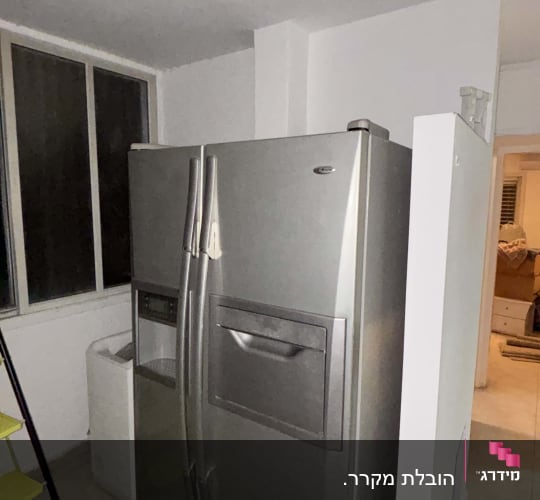 מקרר גדול בחדר עם חלון ומדרגות צהובות